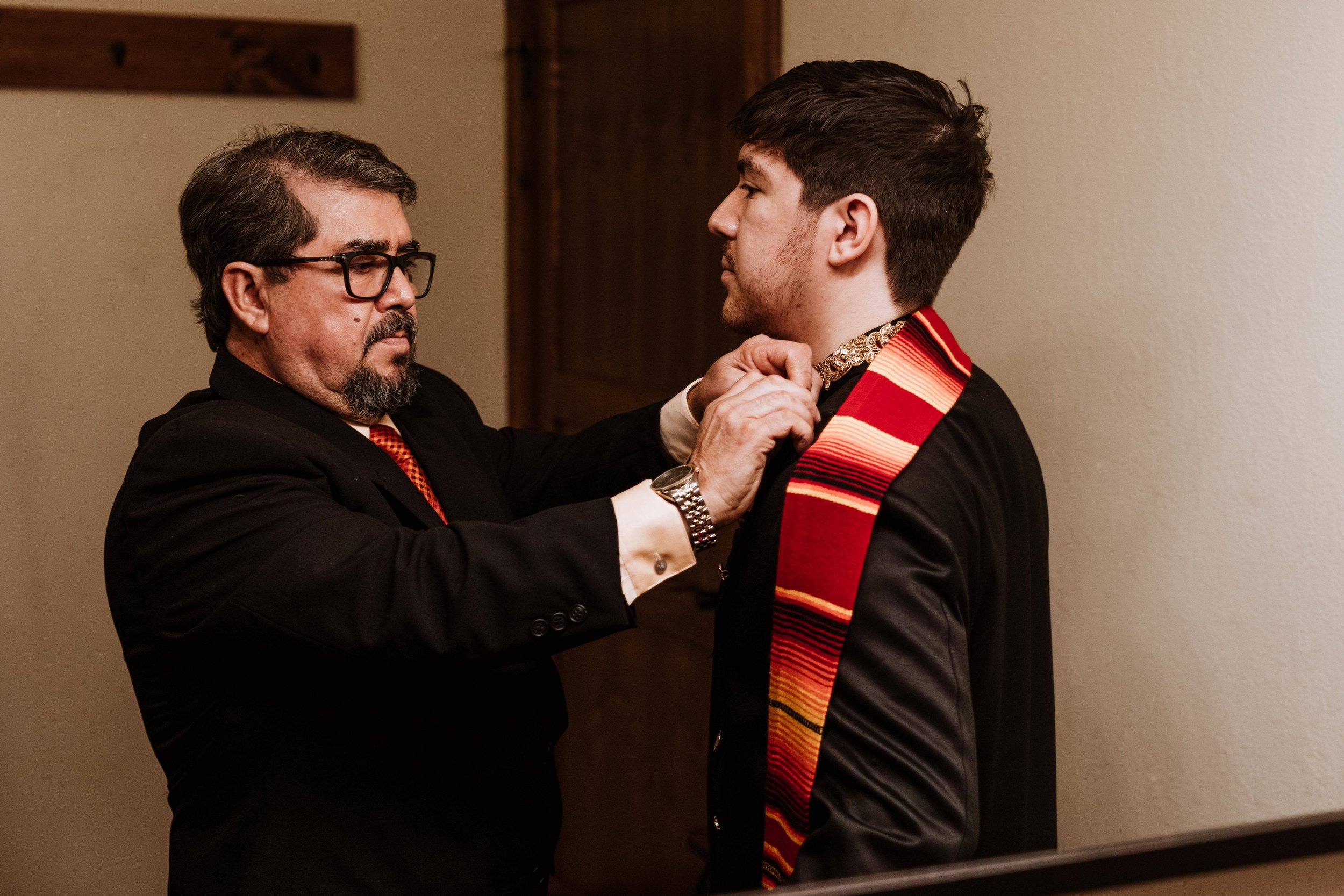 family members help the groom put on the finishing touches on his wedding day