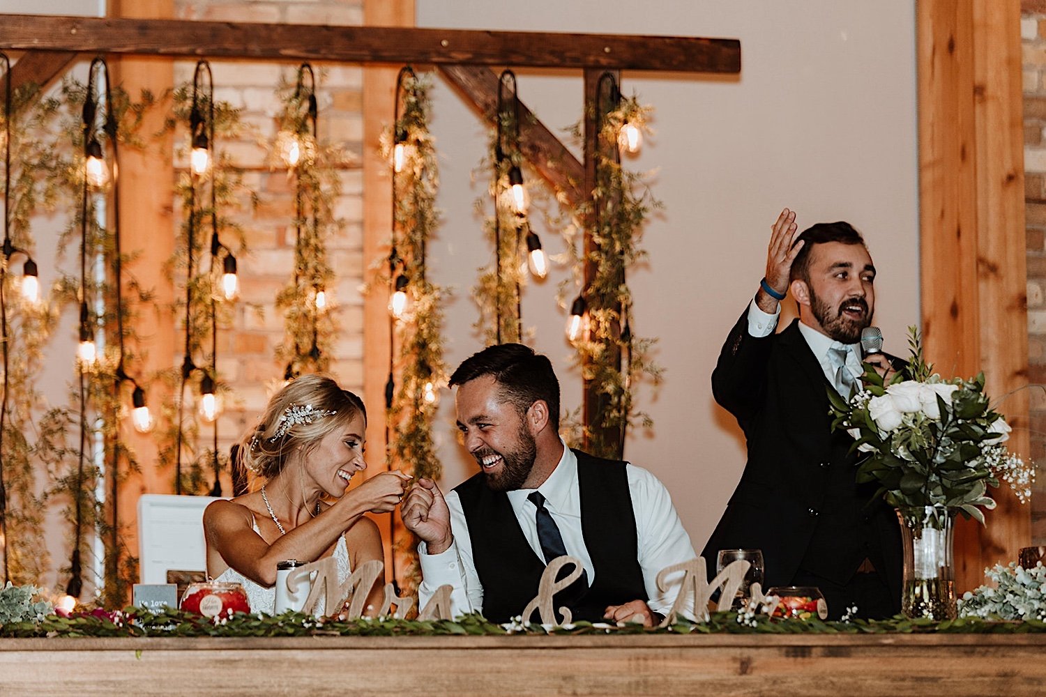 Bride and groom fist bump at their head table