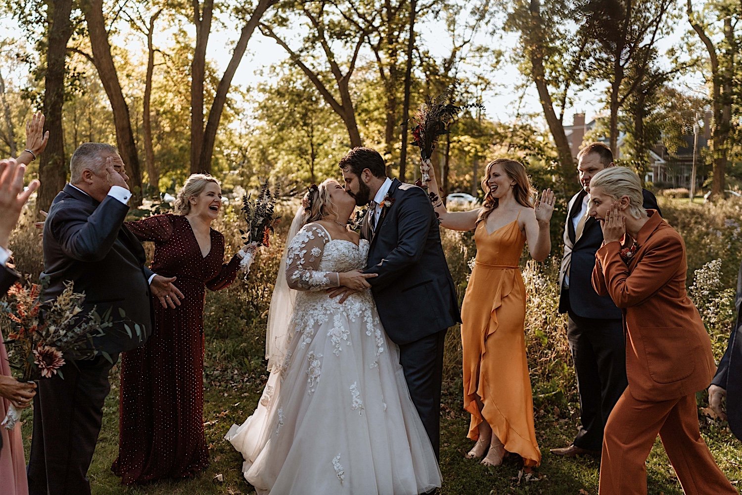 Bride and groom kiss surrounded by wedding party before their Lake Ellyn Boathouse wedding