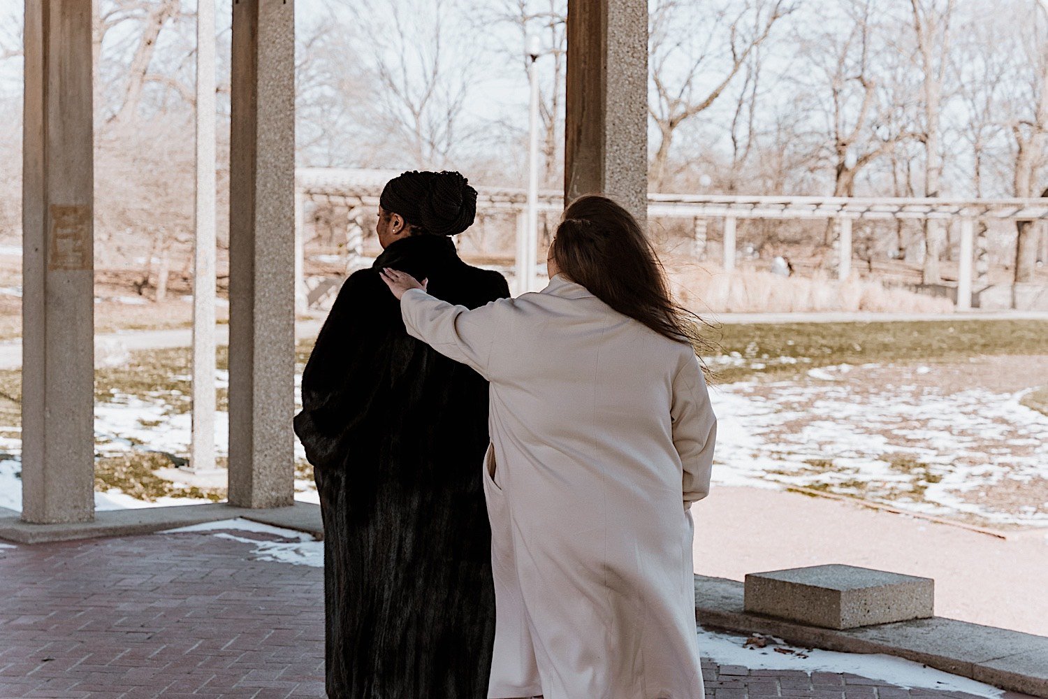 Bride taps her bride's shoulder to get her attention for their first look in the park