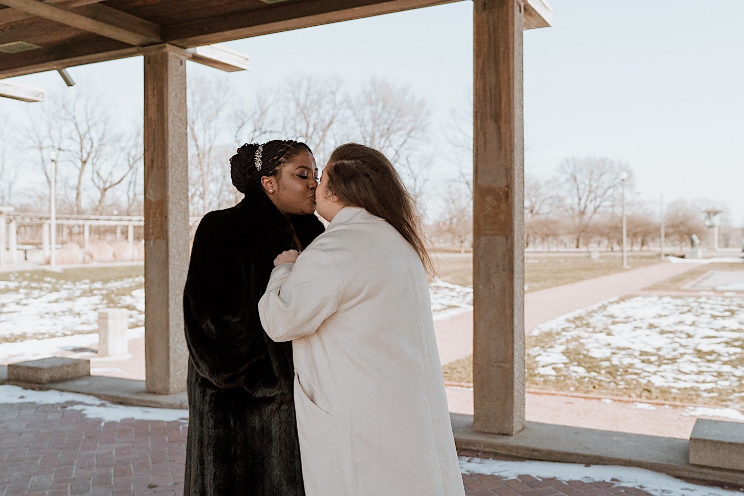 Brides kiss wearing winter coats in Humboldt Park