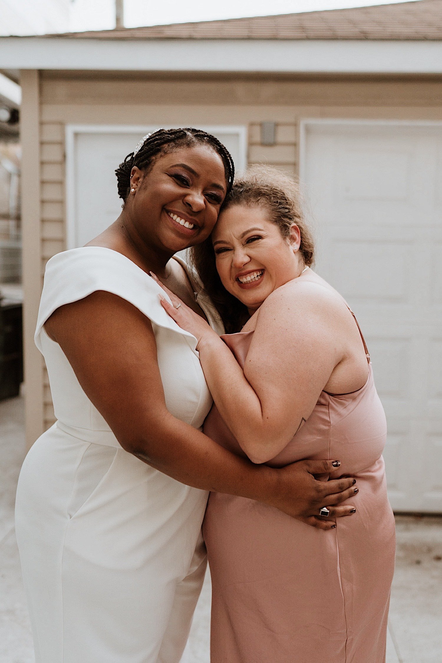 Brides embrace and smile outside their Humboldt Park wedding venue