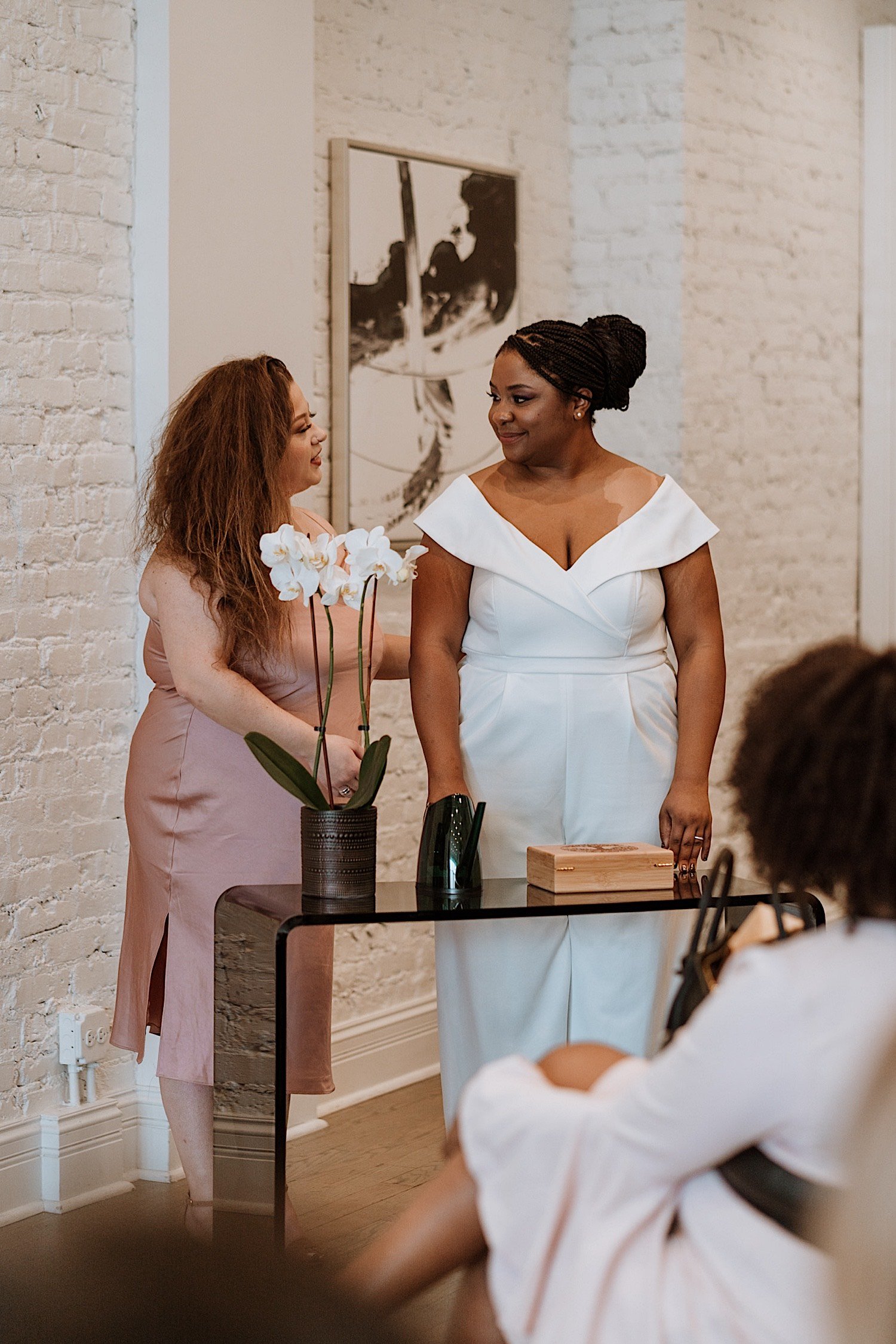 Brides stand next to each other in front of table during their wedding ceremony