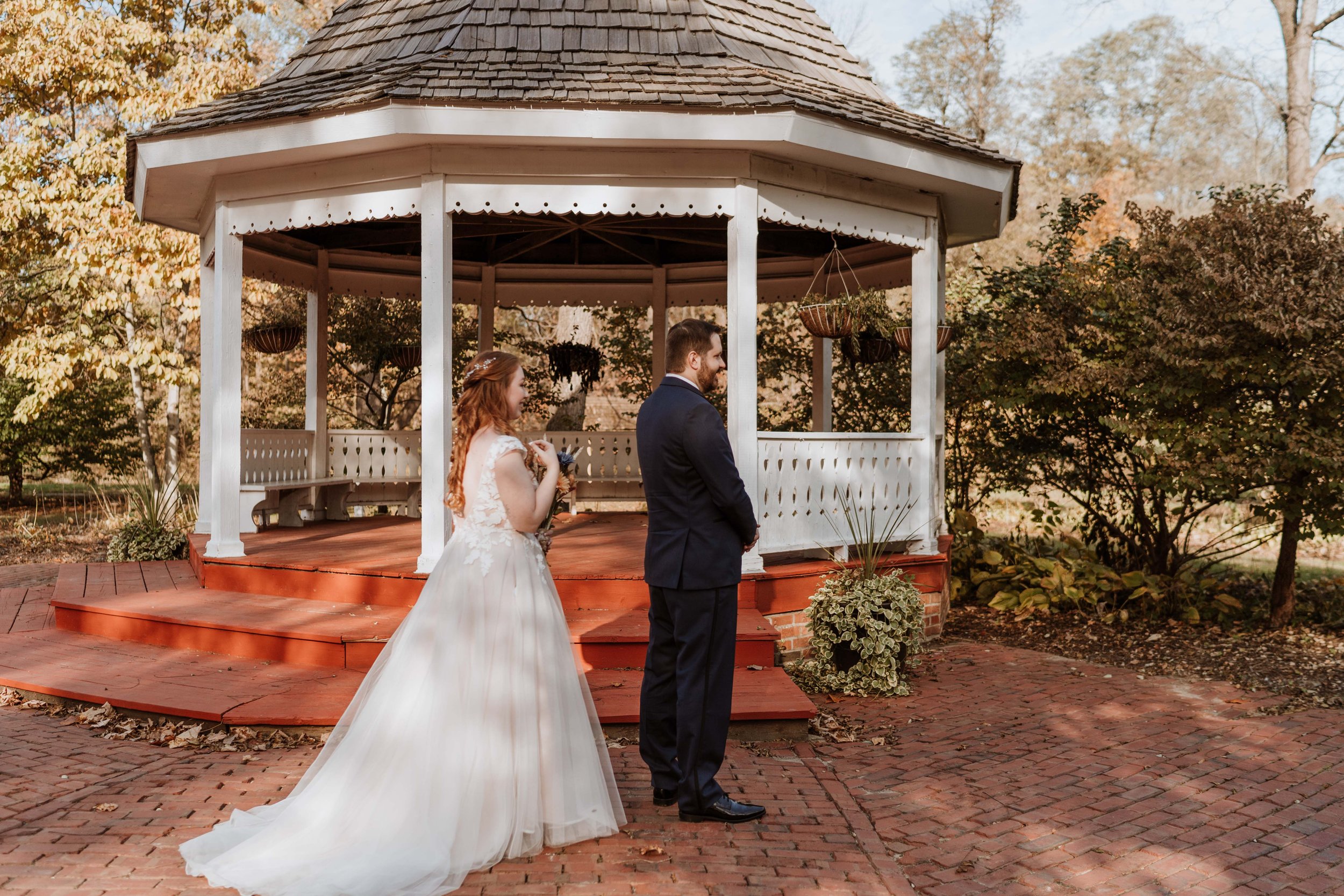 Bride approaches soon to be husband for their first look in front of a white gazebo