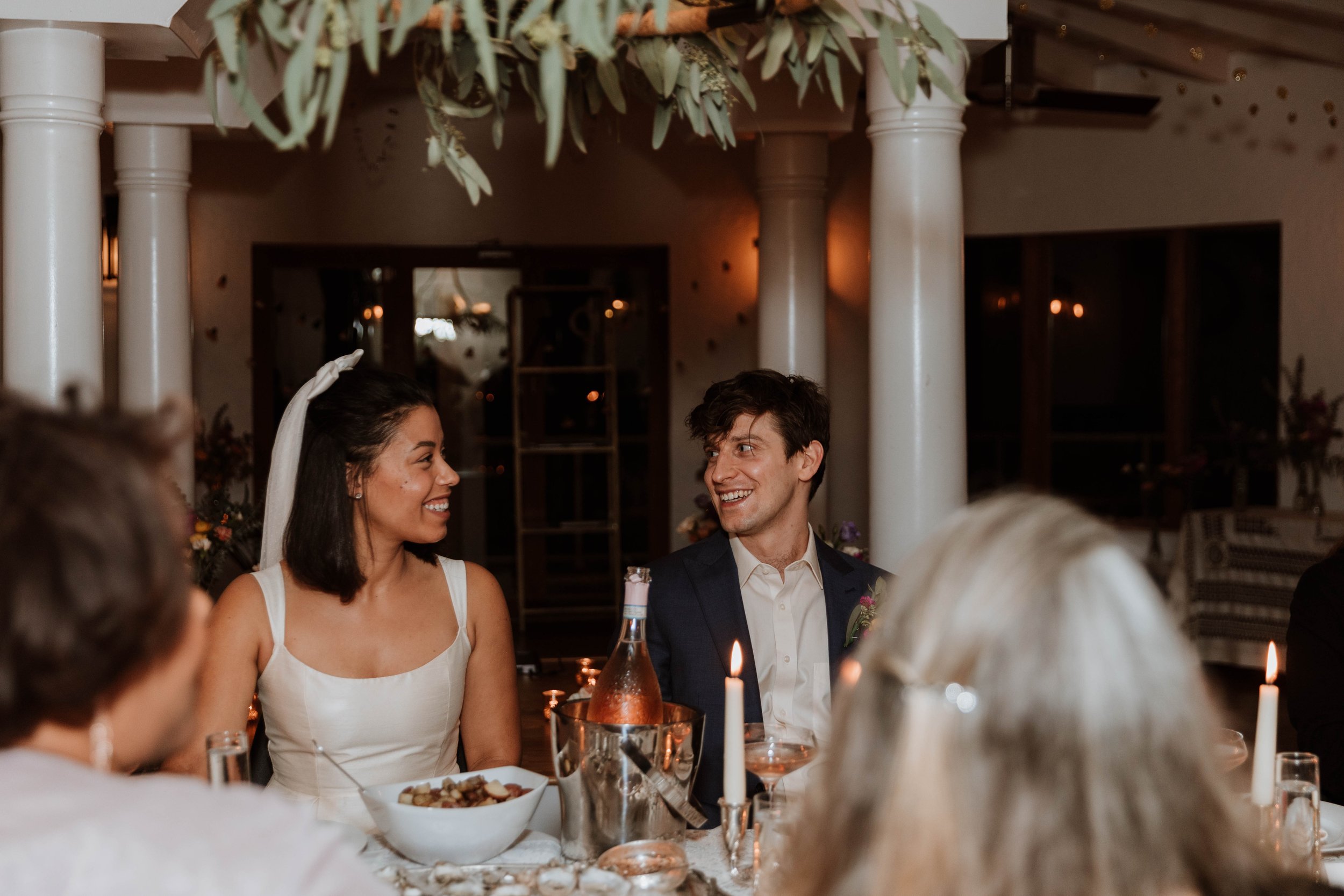 Bride and groom smiling at their wedding reception dinner