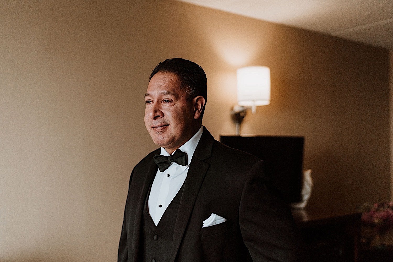 Father sees his daughter in her wedding dress and smiles while getting ready in a hotel room