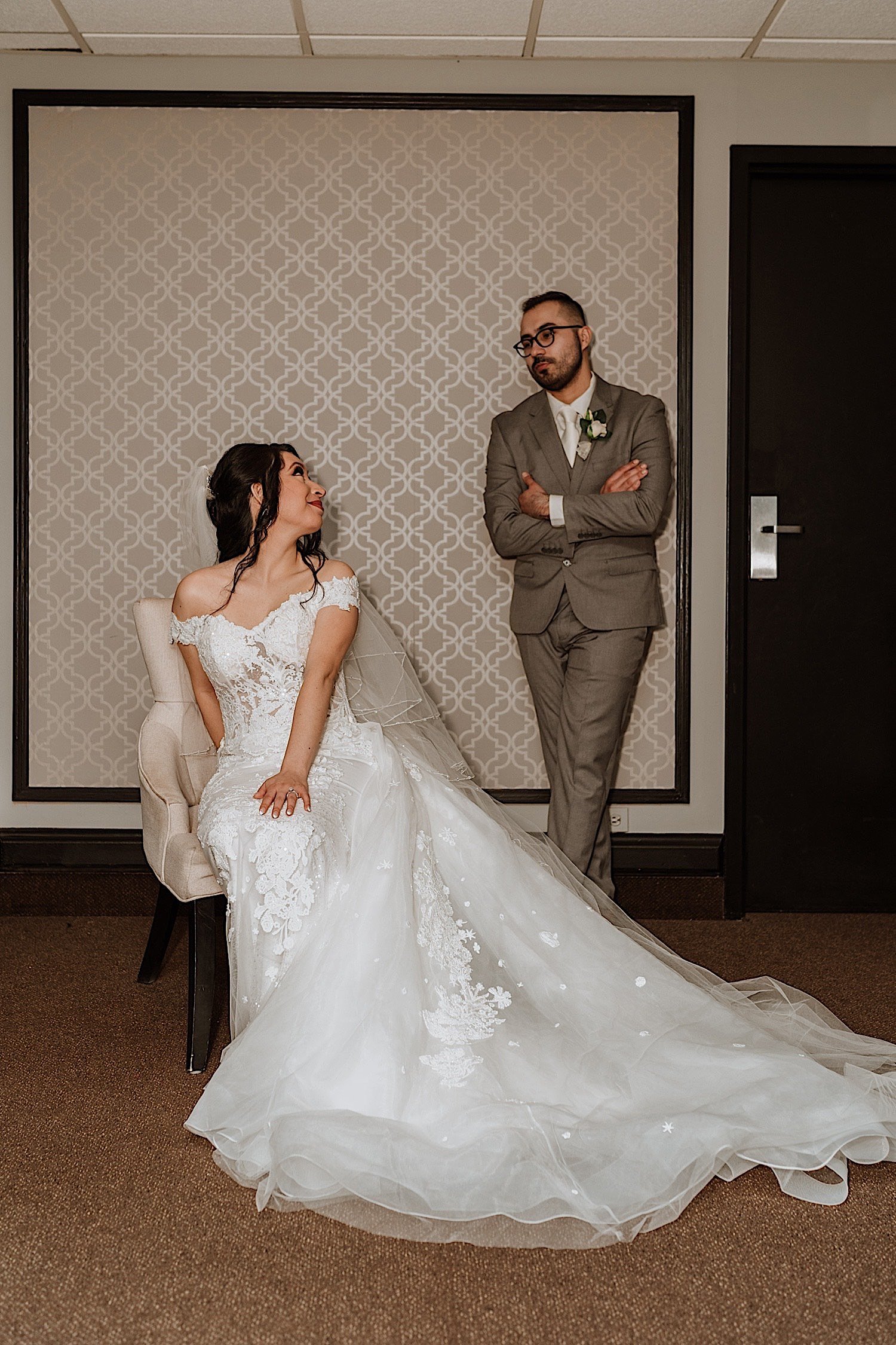 Seated bride looks back and smiles at groom standing behind her