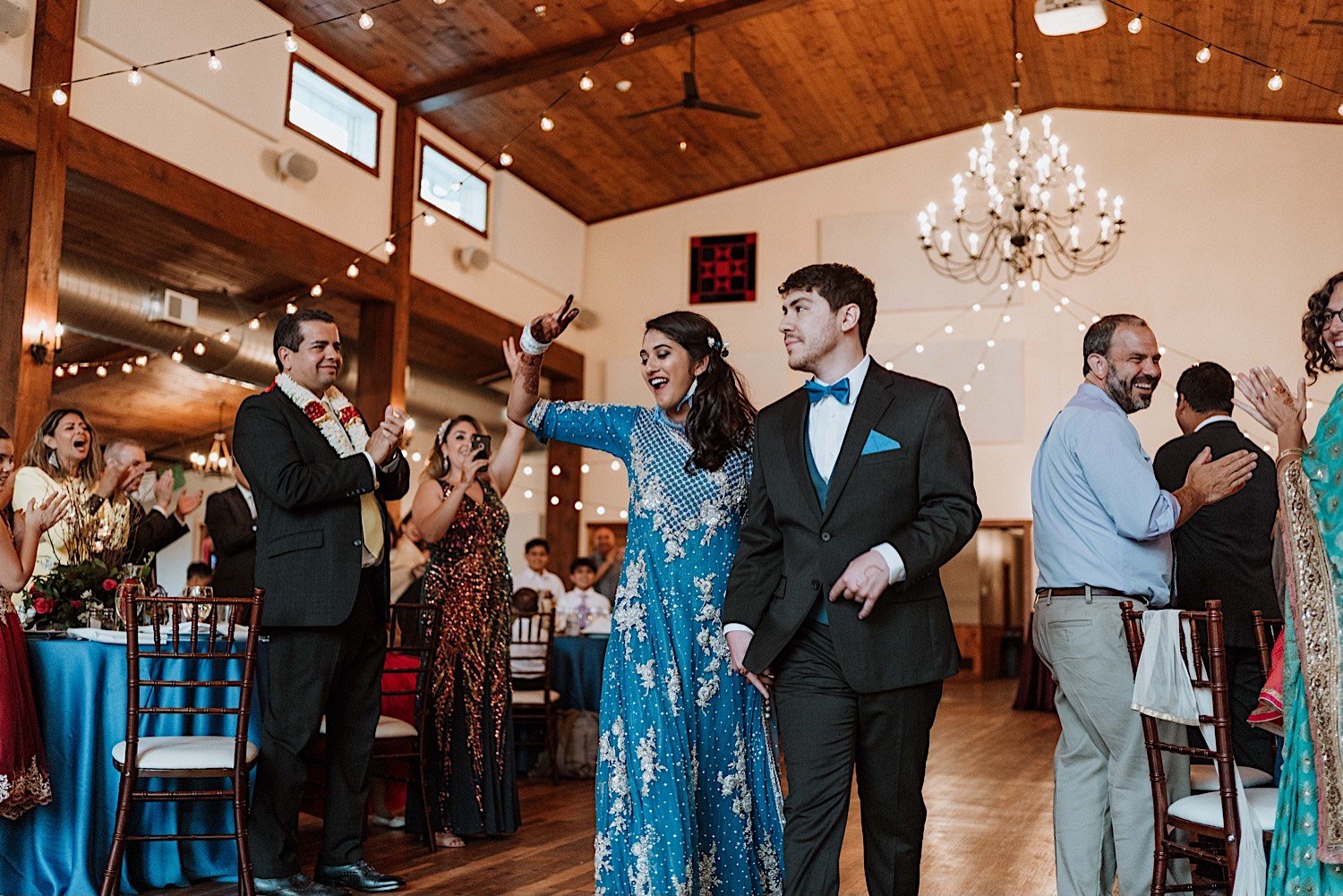 Bride and groom celebrate wedding reception entrance while their friends and family cheer them on