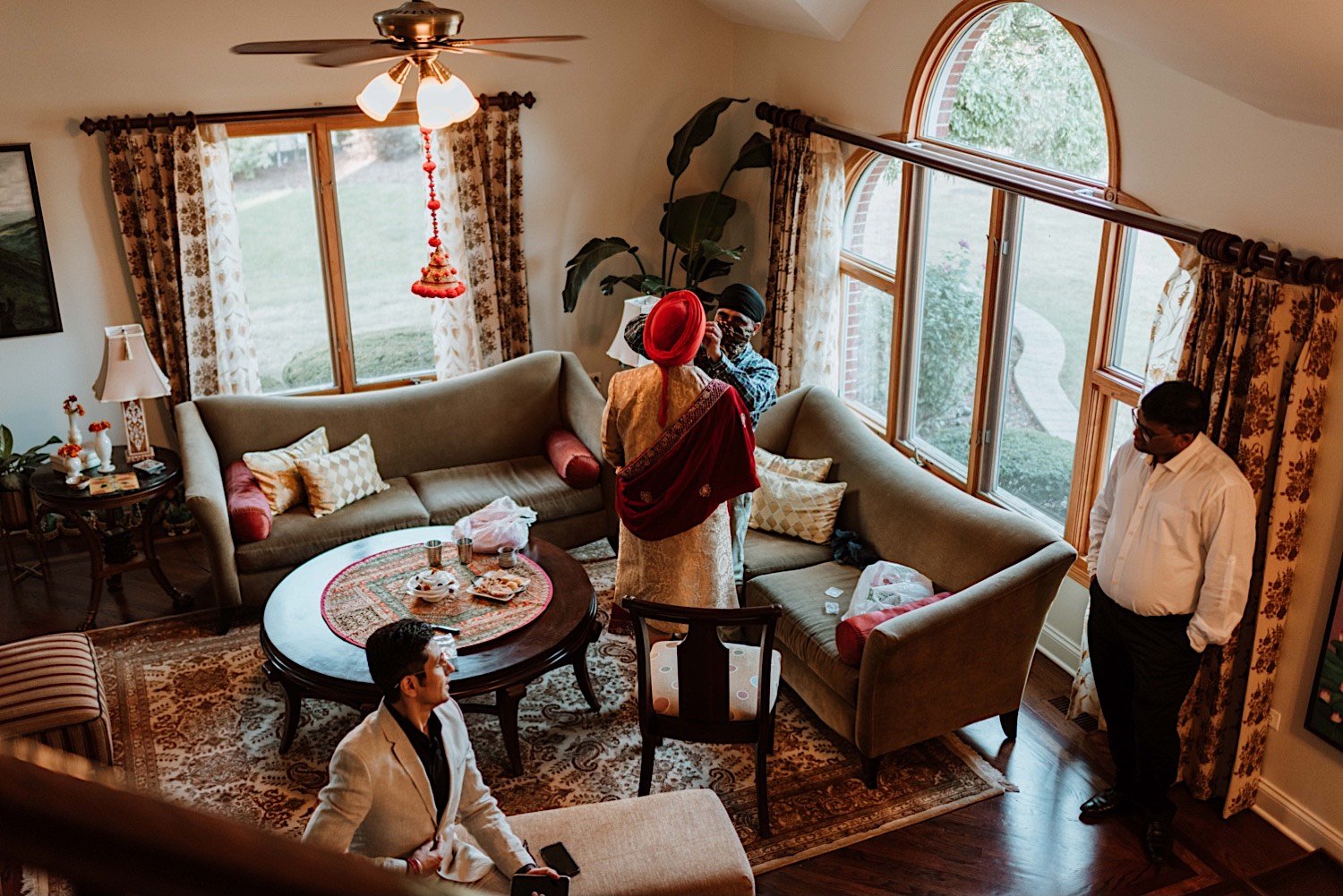 Family helping groom get ready for his wedding in the living room of their house