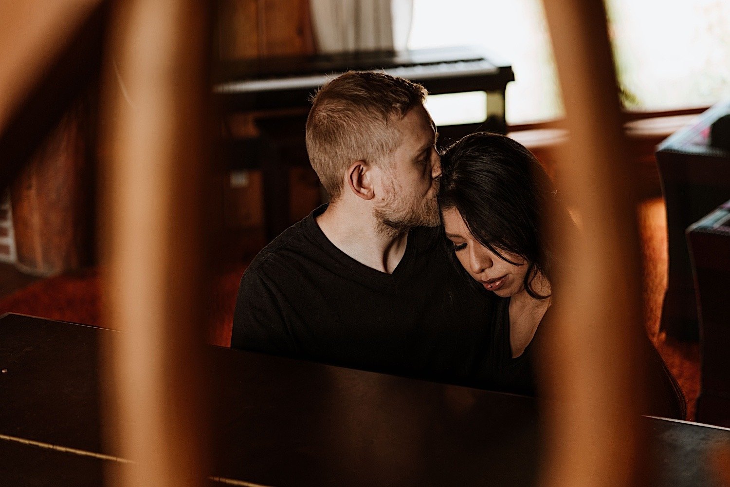 intimate moment of a couple cuddling while the man is kissing the woman's temple.