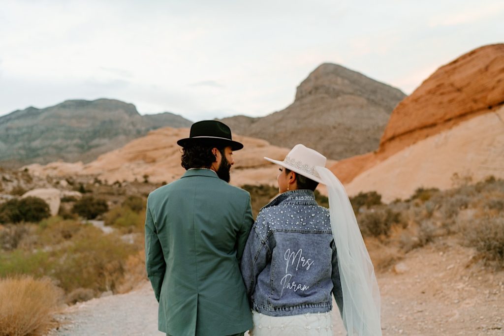 The bride and grooms stand holding hands and looking at one another during their Las Vegas elopement.