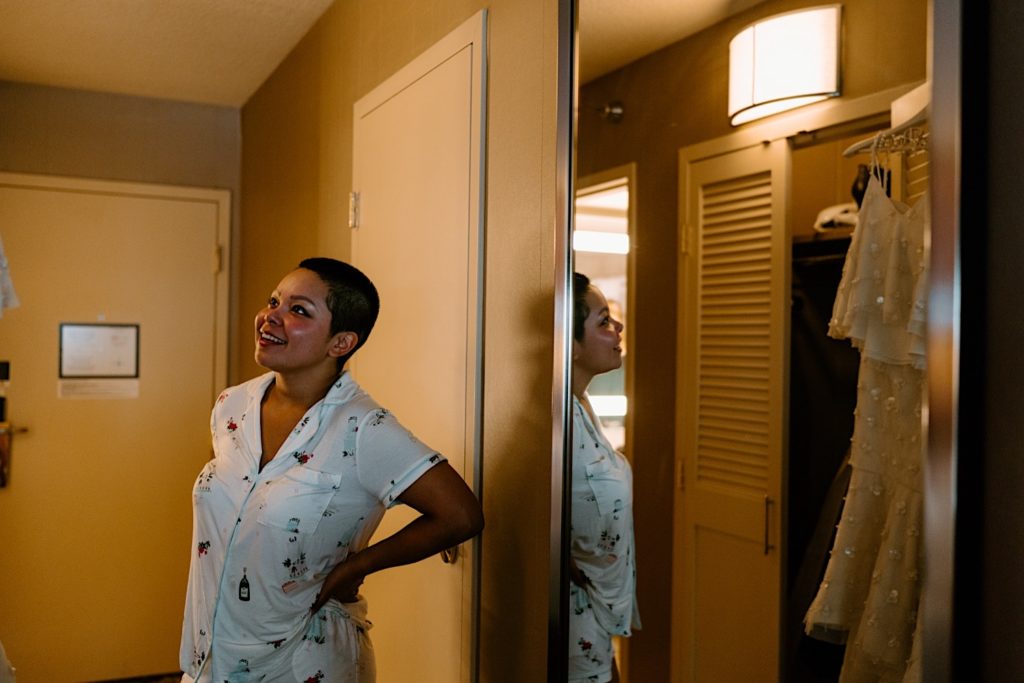 The bride prepping for her wedding day looking at her wedding dress before getting ready.
