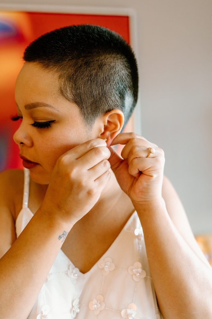 The bride preps for her wedding day putting in her earrings in her Las Vegas hotel room.