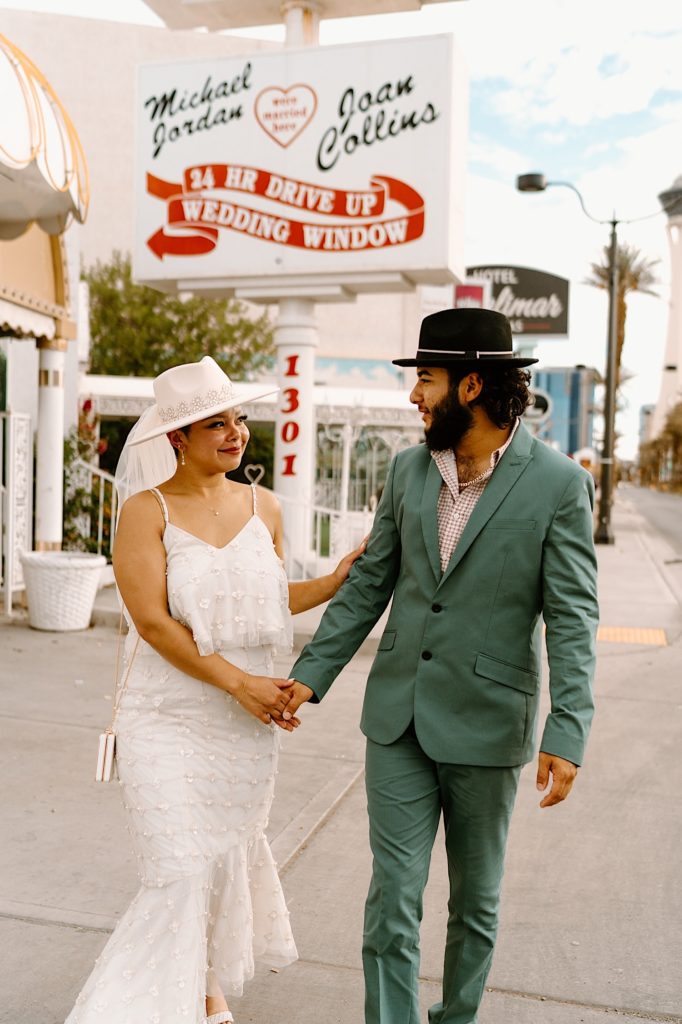 A bride and groom walk towards the White Little Chapel in Las Vegas Nevada.