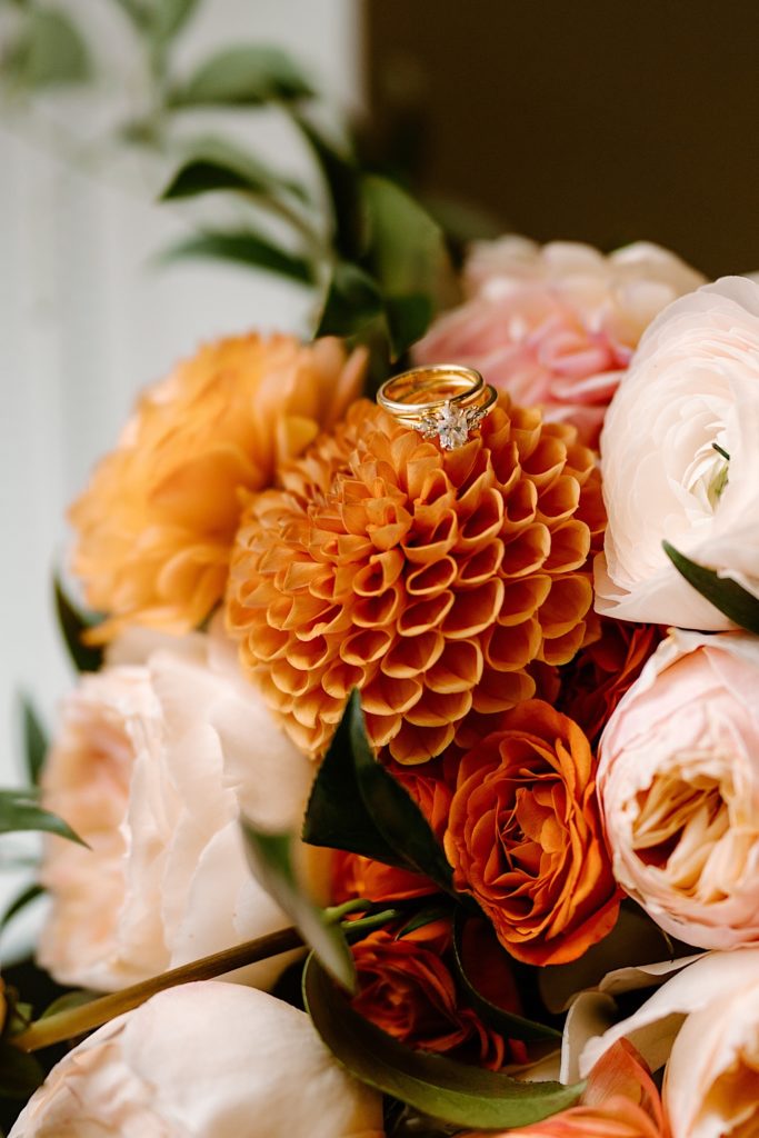 A bridal bouquet with the brides wedding rings sitting on top of the flowers.  