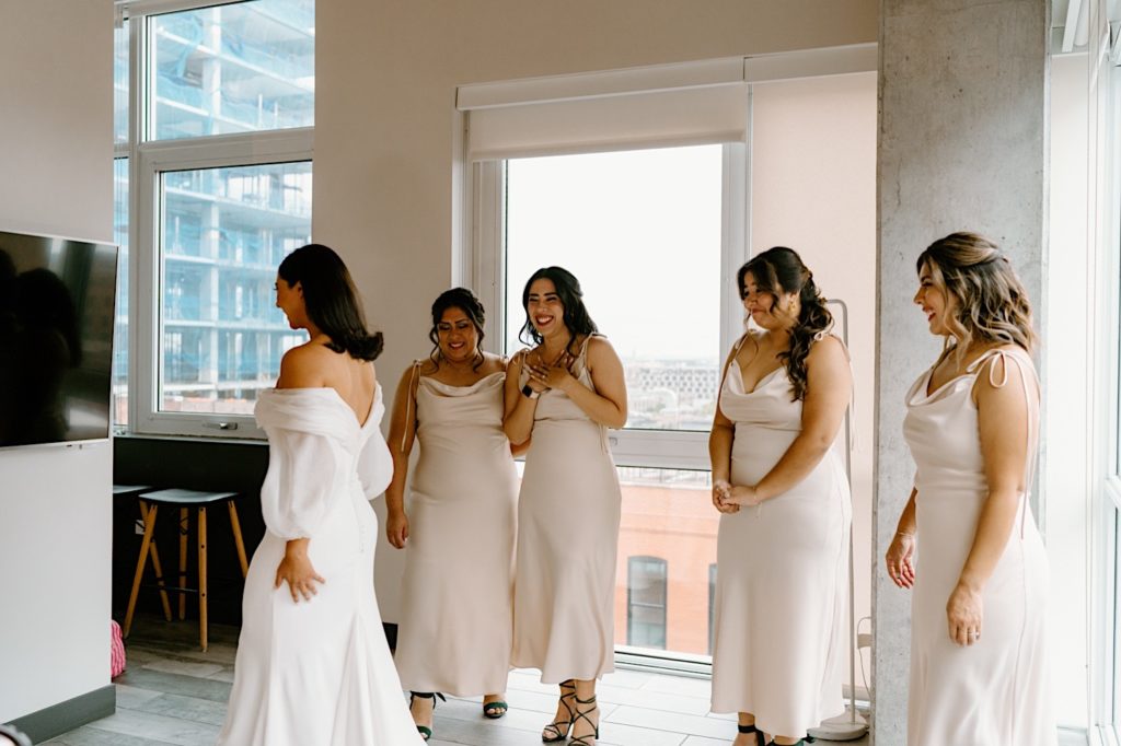 A bride has a first look with her bridesmaids in their Chicago Airbnb.