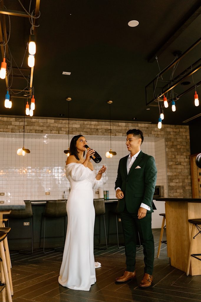 A bride and groom pop champagne to celebrate their wedding day in their Chicago Airbnb.