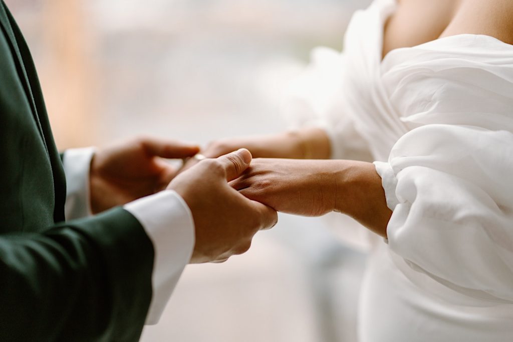 A bride and groom hold hands in front of a window looking over Chicago.