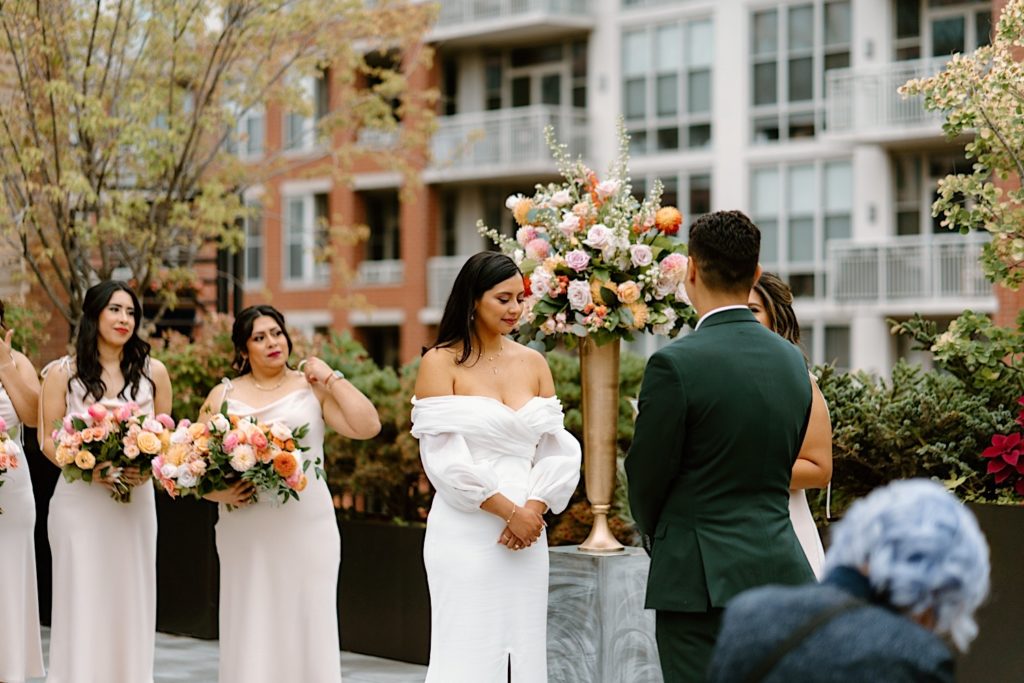 The bride and groom standing during their ceremony at Loft Lucia looking at one another.  