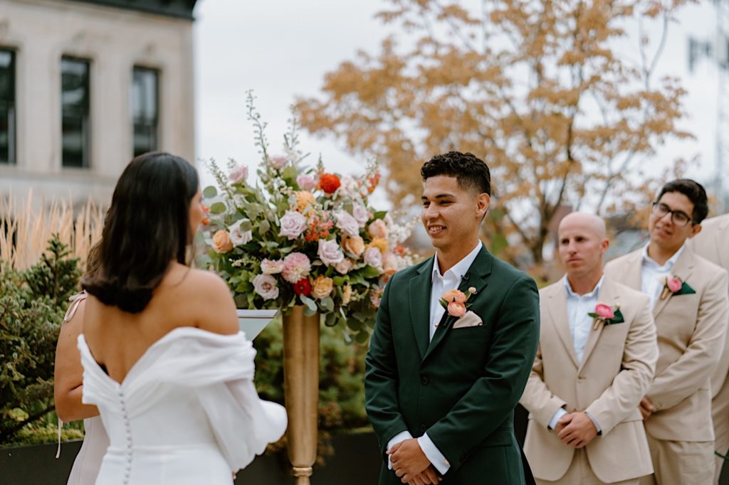 The bride and groom standing during their ceremony at Loft Lucia looking at one another.  