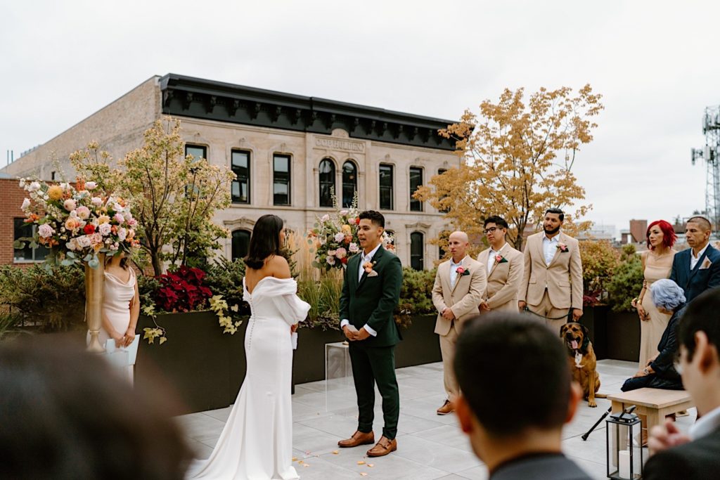 The bride and groom standing during their ceremony at Loft Lucia looking at one another.  