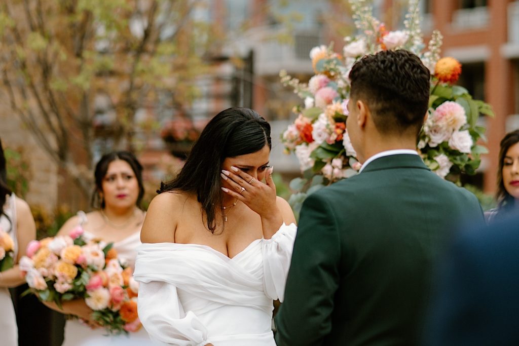 The bride and groom standing during their ceremony at Loft Lucia looking at one another.  
