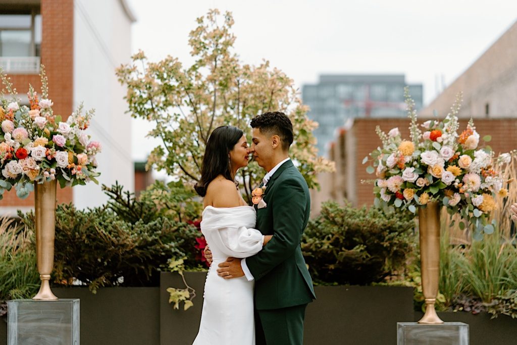 The bride and groom kiss at the end of their ceremony at Loft Lucia surrounded by their loved ones and flowers