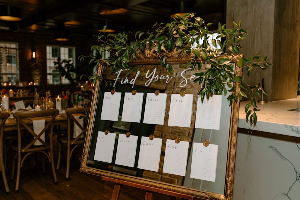 The seating chart on a mirror with greenery surrounding the chart.