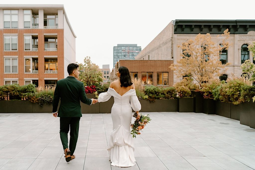 The bride and groom stepping out on the patio holding hands and enjoying the city of Chicago