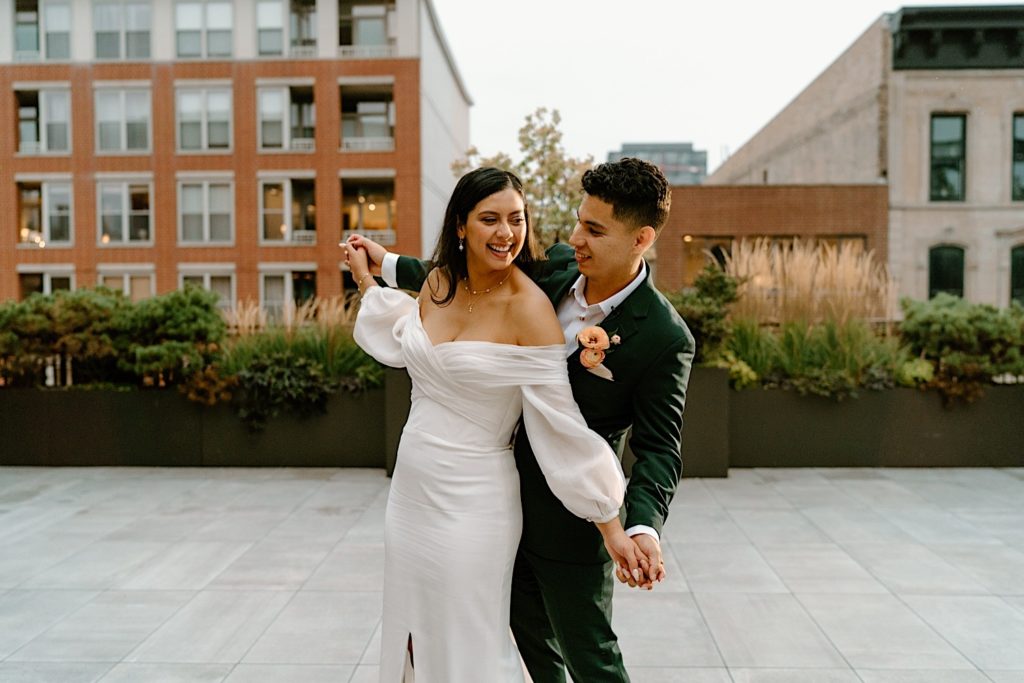 The bride and groom stepping out on the patio holding hands and enjoying the city of Chicago