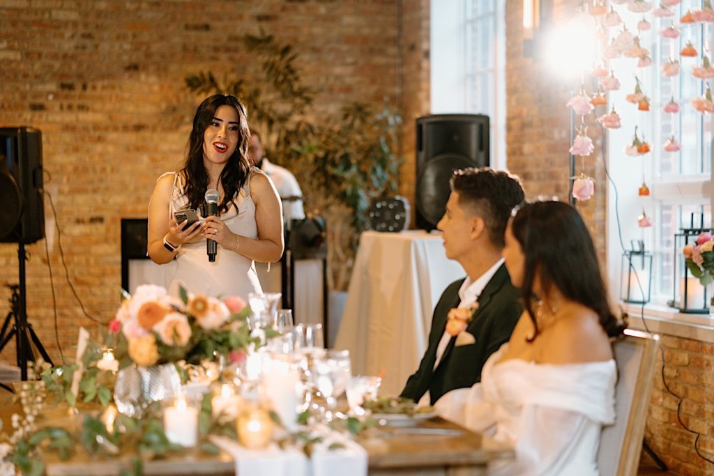 The bride and groom listen to their friend give a toast to them at their Chicago reception.
