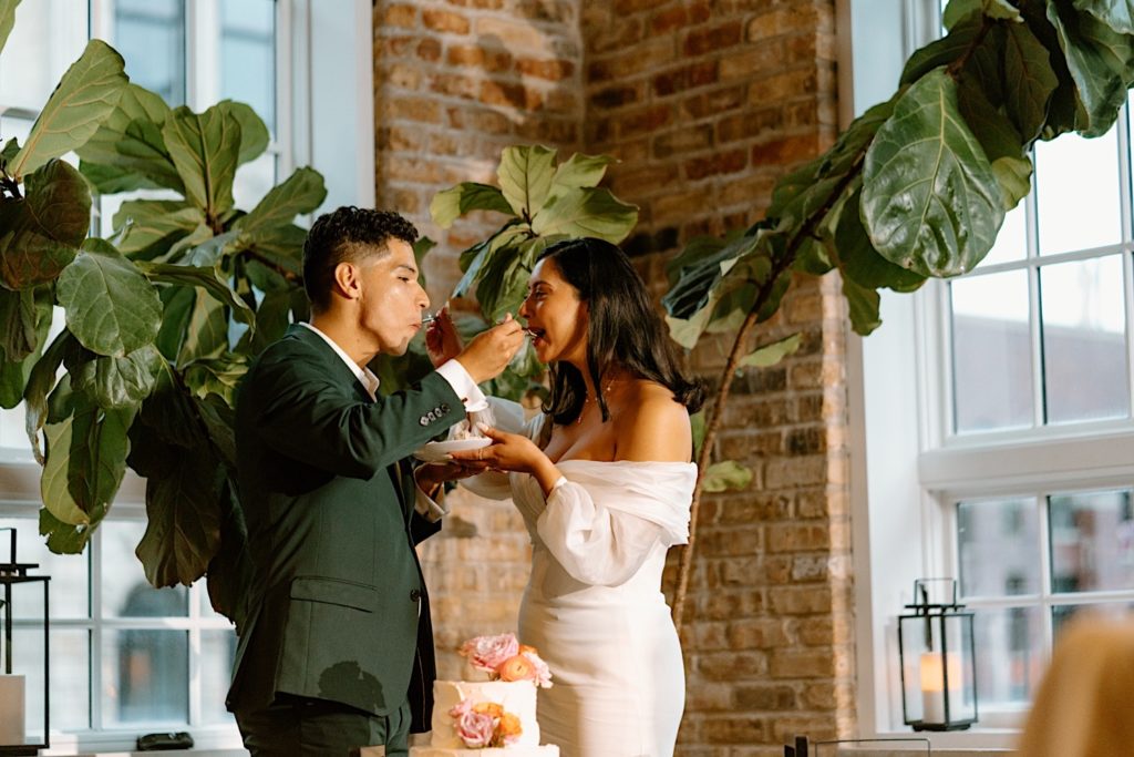 The bride and groom cut their wedding cake during their pink and orange themed wedding reception at Loft Lucia