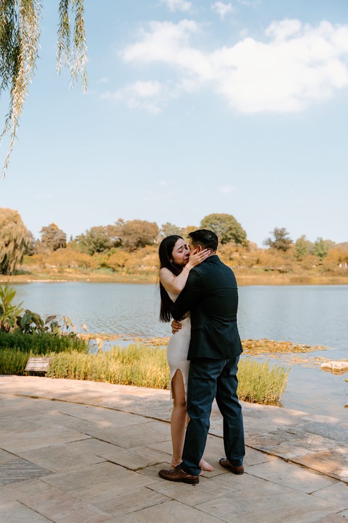 Fiancés kiss while holding one another at the Chicago Botanic Gardens