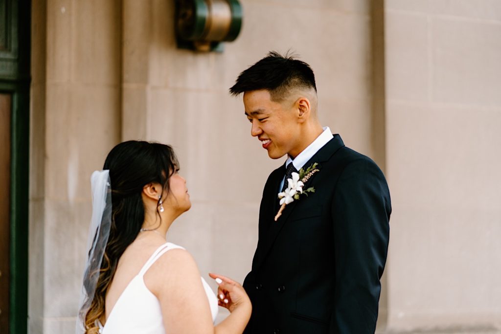A bride and groom stand holding one another during their first look standing underneath the overhand at Joliet's Union Station.