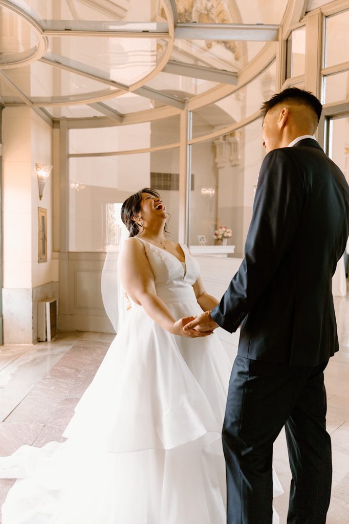A bride and groom stand smiling at one another in the entrance space at Joliet's Union Station.