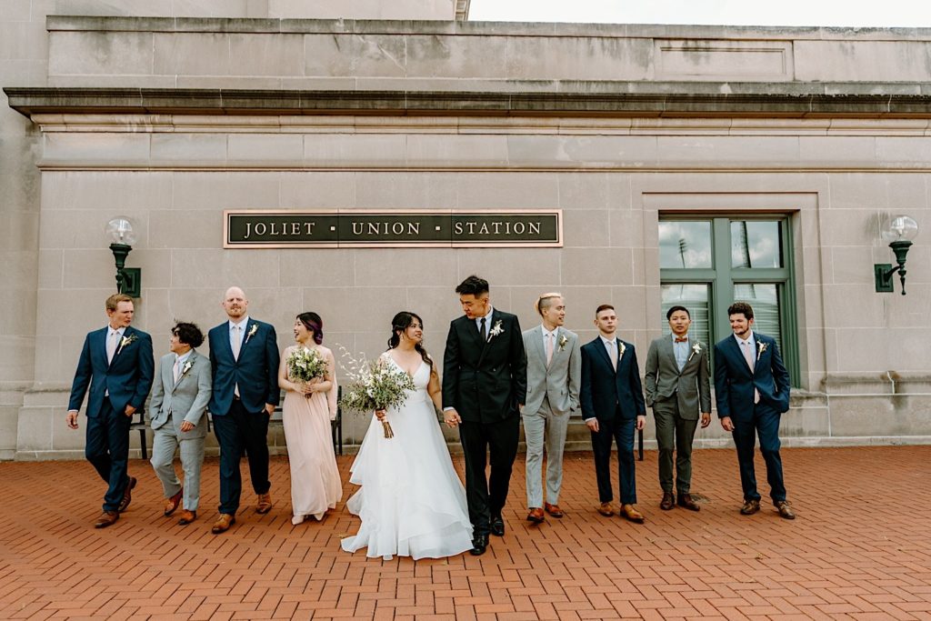 A wedding party stands outside of at Joliet's Union Station posing for portraits.