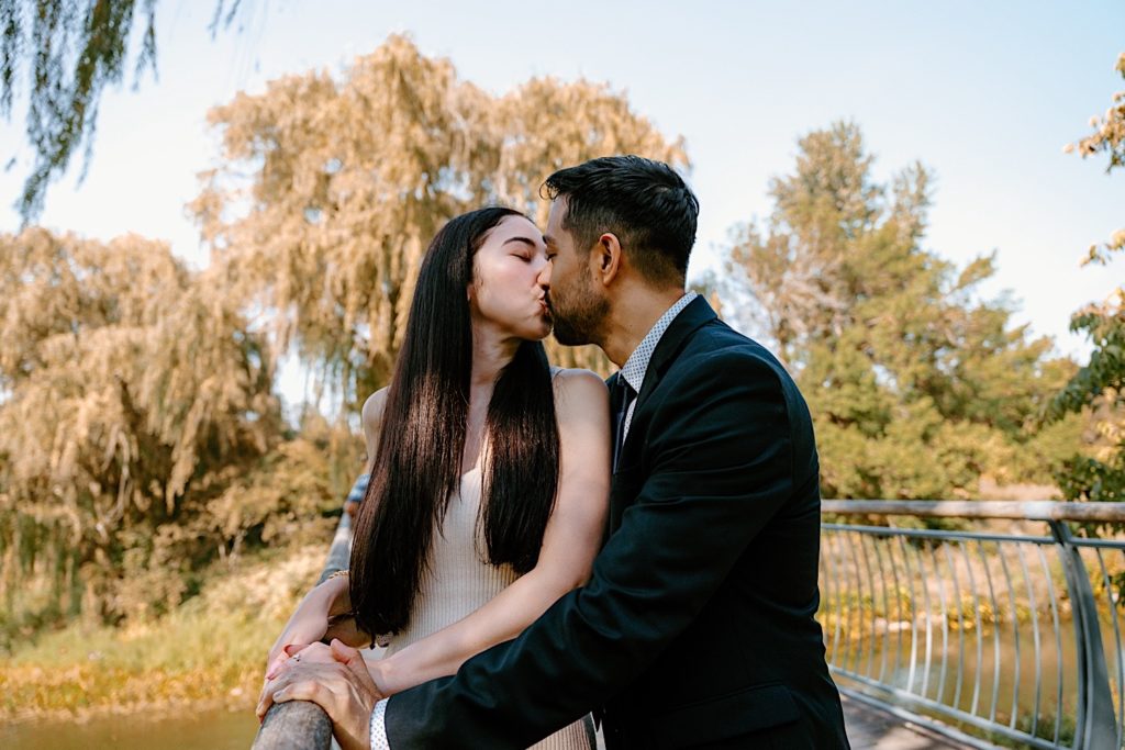 A couple holds one another while kissing on a bridge at the Chicago Botanic Gardens.