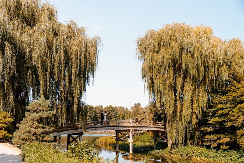 A couple holds one another while kissing on a bridge at the Chicago Botanic Gardens.