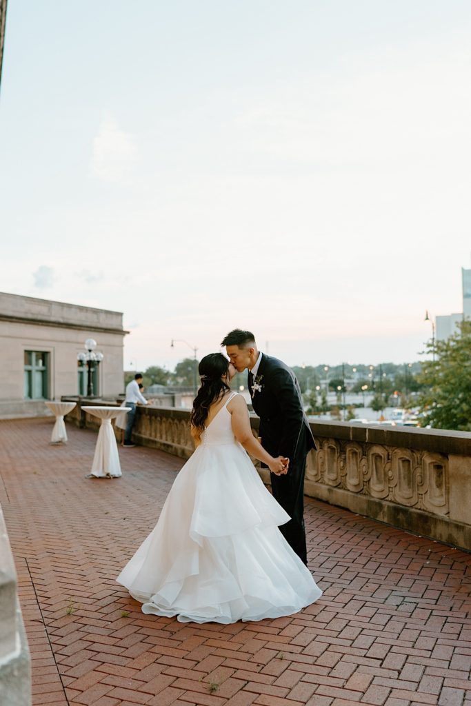 A bride and groom dance while kissing on the balcony at Joliet Union Station. 