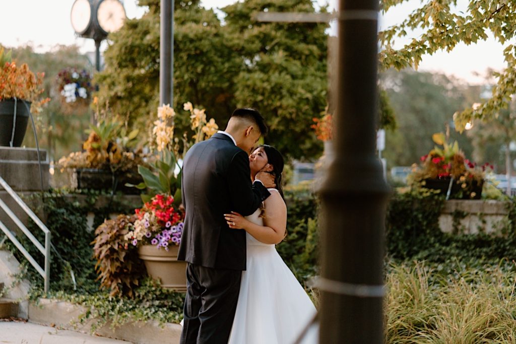A bride and groom stand in the gardens outside of Joliet Union Station during their wedding portraits.