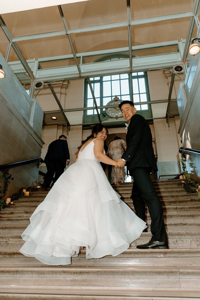 The bride and groom walking up the stairs to their wedding reception.  
