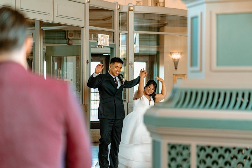 The bride and groom walk into the reception at Joliet Union Station celebrating with their guests.