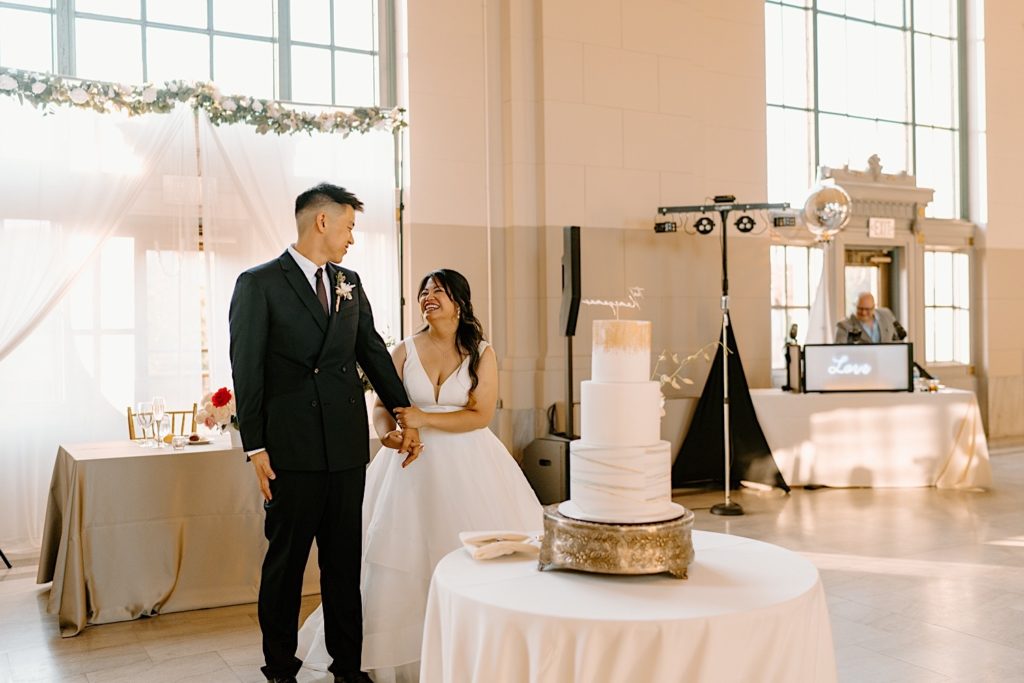 The bride and groom walk into the reception at Joliet Union Station celebrating with their guests.