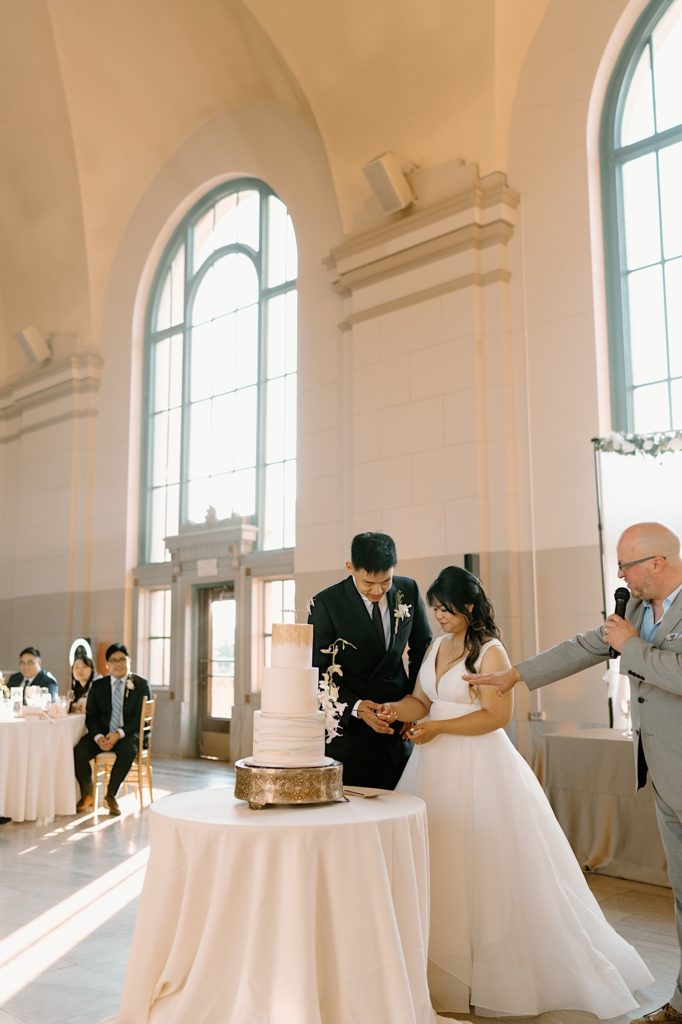 The bride and groom go to cut their cake at the reception at Joliet Union Station celebrating with their guests.