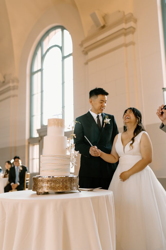 The bride and groom go to cut their cake at the reception at Joliet Union Station celebrating with their guests.