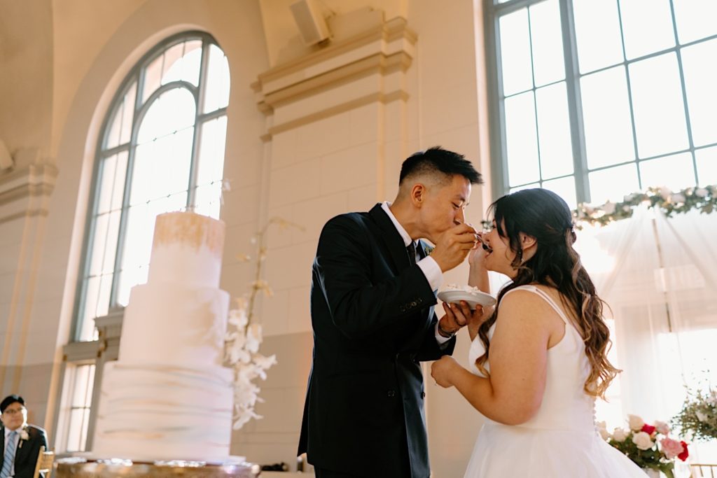 The bride and groom go to cut their cake at the reception at Joliet Union Station celebrating with their guests.