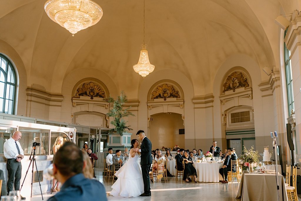 The bride and groom have their first dance at their wedding reception at Joliet Union Station celebrating with their guests.