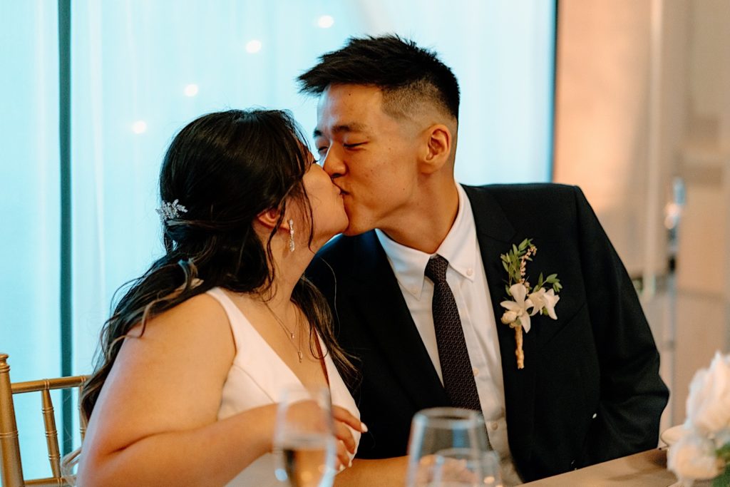 Newlyweds kiss during dinner at their reception at Joliet Union Station