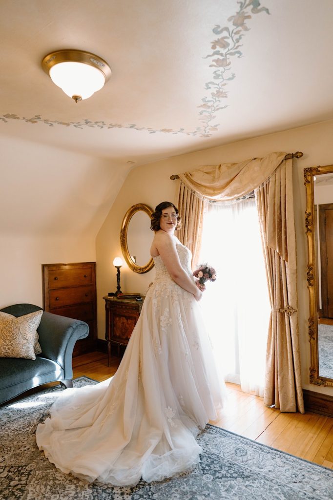 A bride standing in their wedding dress in the dressing room at the Redfield Estates.