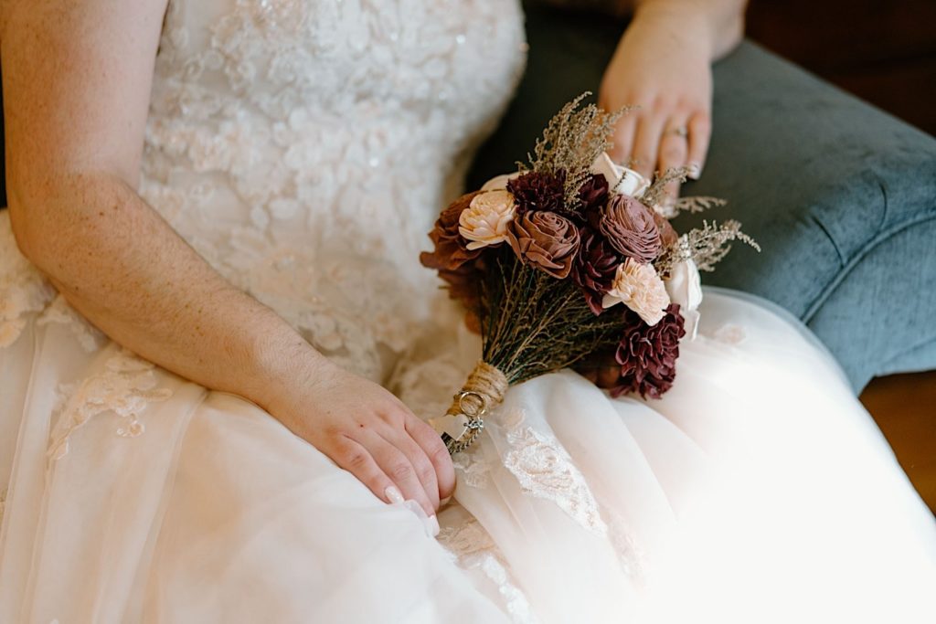 The brides pink dried flowers sitting on the brides lap.
